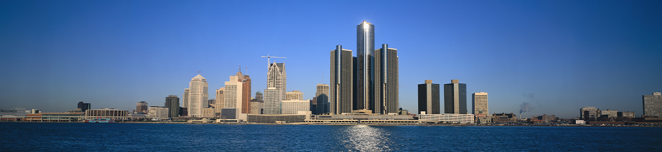 Panoramic view of a city skyline across a body of water with clear blue skies.
